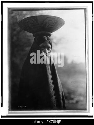 Maricopa fille, portrait mi-long, debout, face légèrement à droite, enveloppée dans une couverture, avec plateau de panier sur la tête, fait partie de : Edward S. Curtis Collection ., Curtis no. 2189-07.. Indiens d'Amérique du Nord, enfants, 1900-1910. , Indiens Maricopa, enfants, 1900-1910. , Paniers, 1900-1910. Banque D'Images