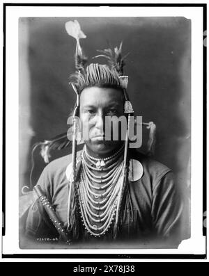 Avalez oiseau, Crow Indian, Montana, portrait de la tête et des épaules, face avant, pompadour peint, coiffe Apsaroke, chemise en flanelle, perles sur la poitrine, pipe cloutée tenue devant le bras droit, collection Edward S. Curtis., Curtis no. 2678-08.. Avalez oiseau. , Indiens d'Amérique du Nord, Montana, vêtements et robes, 1900-1910. , Crow Indians, vêtements et robes, 1900-1910. Banque D'Images