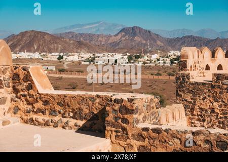 Vue depuis le château de Jabreen à Oman à travers des plaines désertiques vers une ville voisine, avec des remparts en pierre et des montagnes escarpées au-delà. Construit en 1675 Banque D'Images