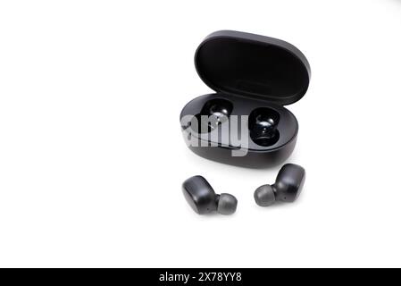 Casque sans fil isolé sur un fond blanc. Micro-casque/oreillette gros plan dans l'étui de chargement gros-plan Banque D'Images
