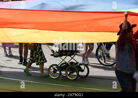 Cracovie, Pologne, 18 mai 2024. Une femme avec un bogie marche sous le drapeau de la Pride alors que les participants marchent dans la 20e Pride Parade à Cracovie, car ils peuvent se sentir plus détendus après qu'un parti plus centro-libéral a gagné le pouvoir après 8 ans de règles de droite. Les défilés de la fierté en Pologne ont eu une histoire d'attaques violentes dans le passé tandis que le gouvernement actuel est heureux de se joindre aux défilés. Crédit : Dominika Zarzycka/Alamy Live News. Banque D'Images