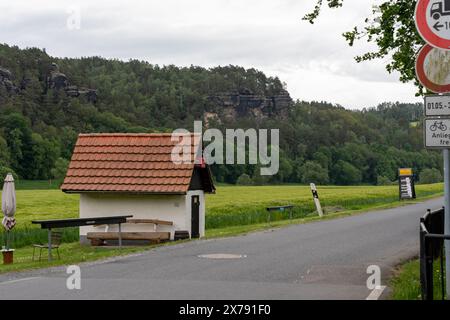 Une petite maison rouge avec un toit blanc se trouve dans un champ. La maison est entourée d'arbres et d'herbe Banque D'Images