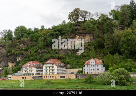 Une colline avec une rangée de maisons et un grand arbre. Les maisons sont blanches et rouges, et la colline est couverte d'arbres verts. La scène a un paisible et s. Banque D'Images