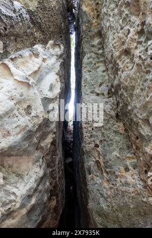 Une crevasse étroite dans un mur de roche avec un petit trou dedans. Le trou est éclairé par le soleil Banque D'Images