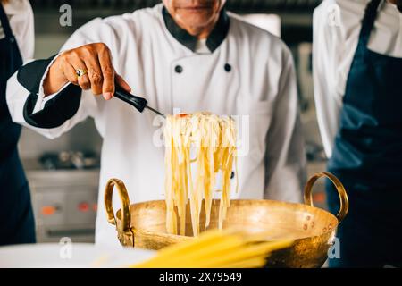 Dans la cuisine chef éduque les étudiants. Des écolières en uniforme font de la soupe ramen. Enfants au poêle avec Banque D'Images