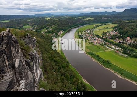 Une rivière traverse une ville avec des maisons et un pont. La rivière est entourée d'arbres et d'herbe Banque D'Images