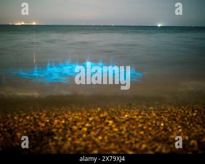 Sheerness, Kent, Royaume-Uni. 18 mai 2024. Météo Royaume-Uni : superbe bioluminescence bleue électrique vive vue à Sheerness Beach dans le Kent ce soir - la couleur est créée lorsque le plancton bioluminescent est perturbé. Les photos montrent des vagues brisées et des pierres jetées dans la mer. Crédit : James Bell/Alamy Live News Banque D'Images