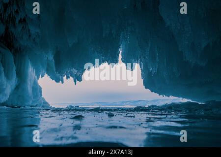 À l'intérieur d'une magnifique grotte de glace sur le lac Baïkal, de grands glaçons pendent du plafond, créant un paysage hivernal à couper le souffle. Les montagnes enneigées peuvent Banque D'Images