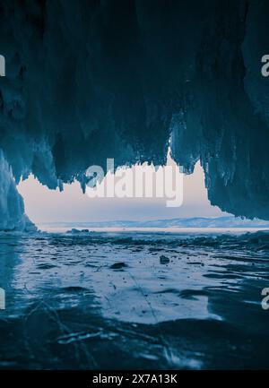 À l'intérieur d'une magnifique grotte de glace sur le lac Baïkal, de grands glaçons pendent du plafond, créant un paysage hivernal à couper le souffle. Les montagnes enneigées peuvent Banque D'Images