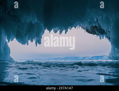 À l'intérieur d'une magnifique grotte de glace sur le lac Baïkal, de grands glaçons pendent du plafond, créant un paysage hivernal à couper le souffle. Les montagnes enneigées peuvent Banque D'Images