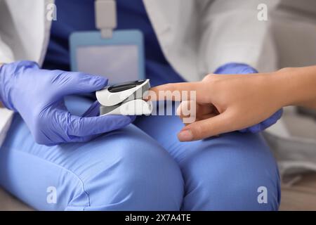 Médecin féminin prenant le pouls du patient à la maison, closeup Banque D'Images