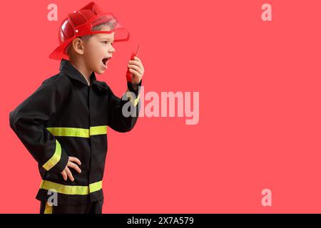 Mignon petit pompier avec émetteur radio sur fond rouge Banque D'Images