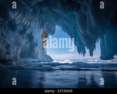 À l'intérieur d'une magnifique grotte de glace sur le lac Baïkal, de grands glaçons pendent du plafond, créant un paysage hivernal à couper le souffle. Les montagnes enneigées peuvent Banque D'Images