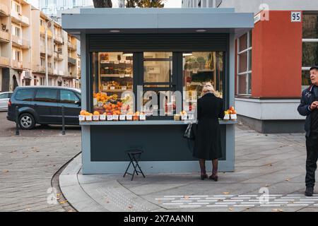 Une femme achète des produits frais dans un petit kiosque de rue dans le centre-ville de Kaunas, en Lituanie Banque D'Images