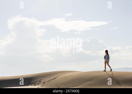 femme dans le désert marchant parmi les dunes au coucher du soleil contre le ciel, copiez l'espace dans le ciel Banque D'Images