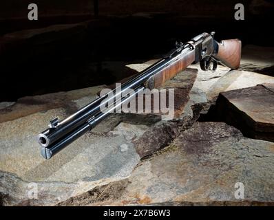 Fusil à levier avec des stocks de bois assis sur des pierres avec un fond sombre. Banque D'Images