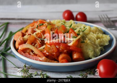 Ragoût de saucisse de pommes de terre au fromage avec des poivrons vibrants, des tomates et du thym frais Banque D'Images