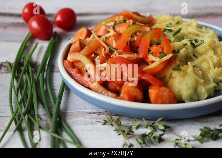 Ragoût de saucisse de pommes de terre au fromage avec des poivrons vibrants, des tomates et du thym frais Banque D'Images