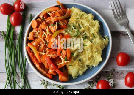 Ragoût de saucisse de pommes de terre au fromage avec des poivrons vibrants, des tomates et du thym frais Banque D'Images