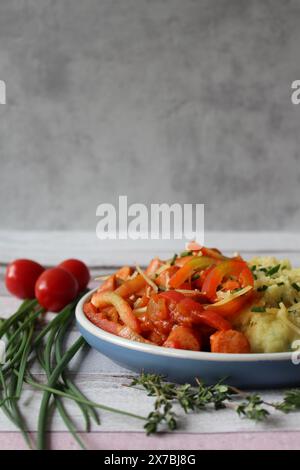 Ragoût de saucisse de pommes de terre au fromage avec des poivrons vibrants, des tomates et du thym frais Banque D'Images