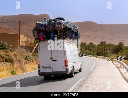 Achbaro, Maroc - 7 mars 2024 : autoroute marocaine avec un camion de transport gravement surchargé livrant des marchandises aux villages du Haut Atlas Banque D'Images