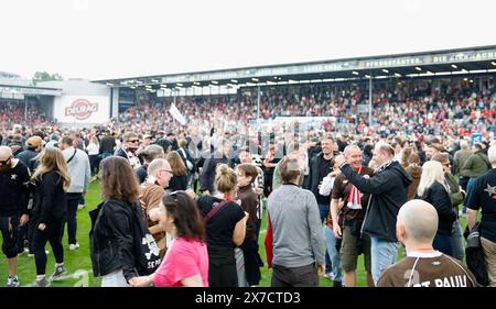 Wiesbaden, Allemagne. 19 mai 2024. Football : Bundesliga 2, SV Wehen Wiesbaden - FC ayant Pauli, Matchday 34, BRITA-Arena. Les fans de Pauli prennent d'assaut le terrain et célèbrent avec l'équipe. Crédit : Heiko Becker/dpa - REMARQUE IMPORTANTE: conformément aux règlements de la DFL German Football League et de la DFB German Football Association, il est interdit d'utiliser ou de faire utiliser des photographies prises dans le stade et/ou du match sous forme d'images séquentielles et/ou de séries de photos de type vidéo./dpa/Alamy Live News Banque D'Images