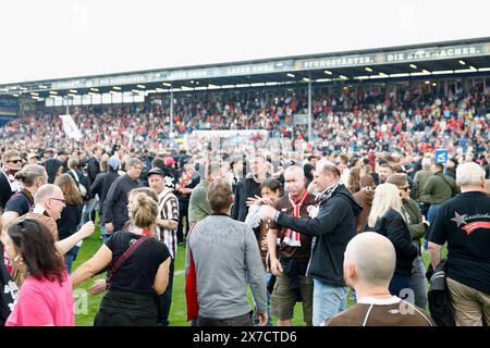 Wiesbaden, Allemagne. 19 mai 2024. Football : Bundesliga 2, SV Wehen Wiesbaden - FC ayant Pauli, Matchday 34, BRITA-Arena. Les fans de Pauli prennent d'assaut le terrain et célèbrent avec l'équipe. Crédit : Heiko Becker/dpa - REMARQUE IMPORTANTE: conformément aux règlements de la DFL German Football League et de la DFB German Football Association, il est interdit d'utiliser ou de faire utiliser des photographies prises dans le stade et/ou du match sous forme d'images séquentielles et/ou de séries de photos de type vidéo./dpa/Alamy Live News Banque D'Images