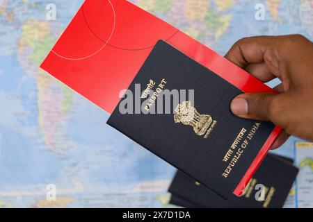 Une photo en gros plan d'un homme sud-asiatique tenant un passeport indien devant une carte du monde colorée, symbolisant la planification de voyage Banque D'Images