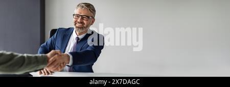 Souriant homme d'affaires d'âge moyen en costume poignée de main avec partenaire Banque D'Images