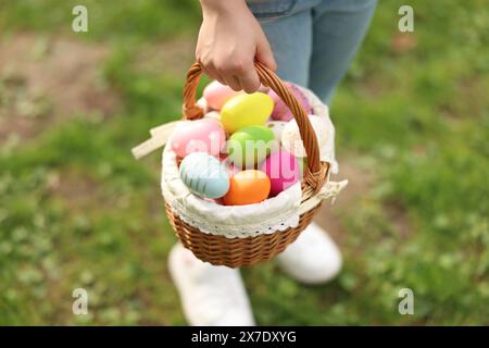 Fête de Pâques. Petite fille tenant un panier avec des œufs peints à l'extérieur, gros plan Banque D'Images