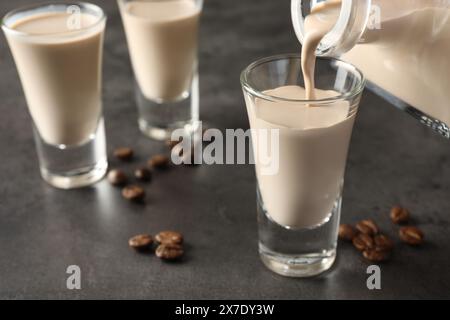 Verser la liqueur de crème de café dans le verre à la table grise, gros plan Banque D'Images