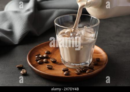 Verser la liqueur de crème de café dans le verre à la table grise, gros plan Banque D'Images