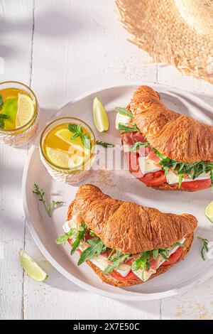 Croissant français frais et fait maison pour le petit déjeuner le matin. Sandwich avec jambon, fromage et légumes. Banque D'Images