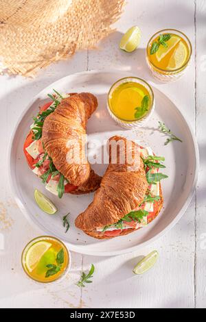Croissant français savoureux et frais avec camembert, prosciutto et tomates. Sandwich avec jambon, fromage et légumes. Banque D'Images
