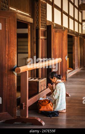 Kyoto, JAPON - 27 juillet 2016 : image verticale d'une femme en prière à l'intérieur du temple. Banque D'Images