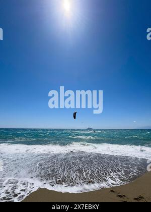 Kitesurfer kite surf dans le vent fort et les vagues mer agitée se déplaçant mer avec voile gonflée, au premier plan vague sortante sur la plage, Kalamaki Banque D'Images