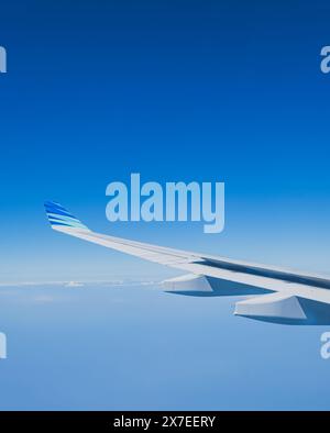 Balikpapan, Indonésie - 6 mai 2024. L'aile d'un avion Garuda Indonesia planant à travers un ciel bleu clair. L'extrémité de l'aile est visible, avec l'airl Banque D'Images