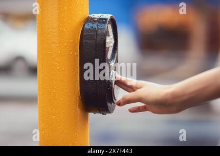 Crosswalk, main et femme avec bouton par feu de circulation pour traverser l'intersection avec la sécurité. Déplacement, signe fléché et piéton féminin à l'arrêt pendant Banque D'Images