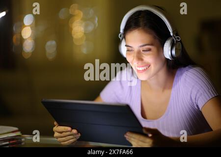 Femme heureuse utilisant la tablette pour regarder des vidéos dans la nuit à la maison Banque D'Images