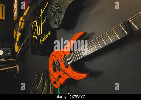 Un gros plan d'une guitare orange avec des rayures noires et blanches accrochées au mur, studio d'enregistrement de musique. Photo de haute qualité Banque D'Images