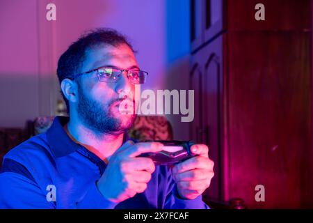 Concept de jeu vidéo. Un gars avec Joystick célébrant la victoire, homme joyeux levant le poing et excitant, debout dans Neon Light Over Banque D'Images