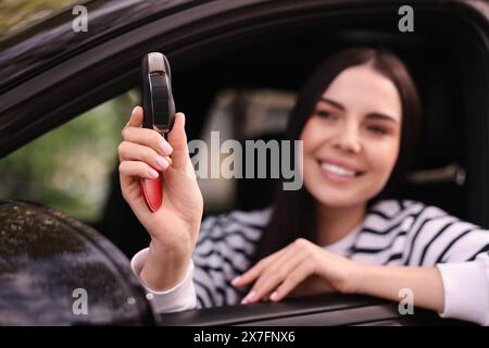 Femme tenant la clé à bascule de voiture à l'intérieur de son véhicule, mise au point sélective Banque D'Images