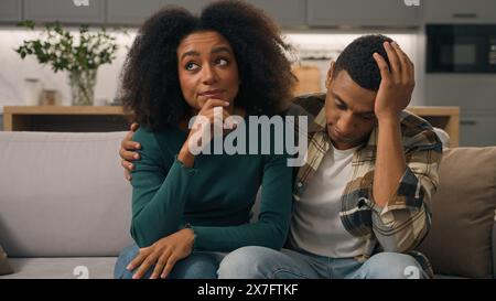 Agacé afro-américain ethnique épuisé jeune couple dérangé parents assis canapé pensant se sentir fatigué à propos bruyant petit garçon enfant hyperactif Banque D'Images