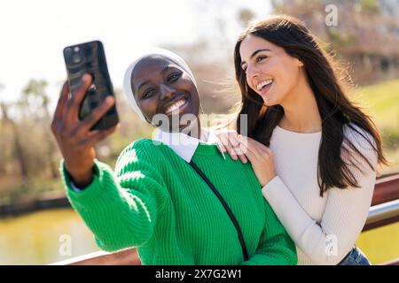 deux jeunes amies riant heureux tout en s'amusant à prendre photo selfie avec téléphone portable dans un parc de la ville, concept d'amitié et de vie moderne Banque D'Images