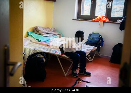 Briançon, France. 19 mai 2024. Un jeune soudanais regarde par la fenêtre de sa chambre qu’il partage avec sa famille au refuge de solidarité, France, Briançon, 19 mai 2024. Médecins du monde maintient une présence permanente aux terrasses solidaires de Briançon, une zone d’accueil pour les migrants qui viennent de franchir la frontière italienne par le col de Montgenèvre. Photo de Thibaut Durand/ABACAPRESS. COM Credit : Abaca Press/Alamy Live News Banque D'Images