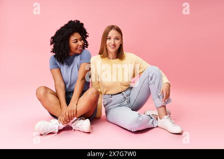 Deux femmes diverses assises sur le sol, les jambes croisées. Banque D'Images