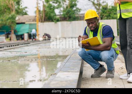 Ingénieur contrôle de qualité dans la fabrication de moulage de béton préfabriqué vérifiant les produits de qualité standard site de construction extérieur, travailleur noir africain Banque D'Images