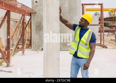 Ingénieur contrôle de qualité dans la fabrication de moulage de béton préfabriqué vérifiant les produits de qualité standard site de construction extérieur, travailleur noir africain Banque D'Images