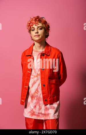 Femme élégante avec les cheveux rouges debout élégamment devant un mur rose vif. Banque D'Images