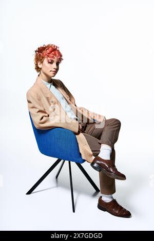 Femme extraordinaire avec les cheveux rouges ardents se détend sur une chaise bleue élégante. Banque D'Images